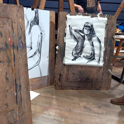 Three easel's upright showing a sketched image of a nude woman.
