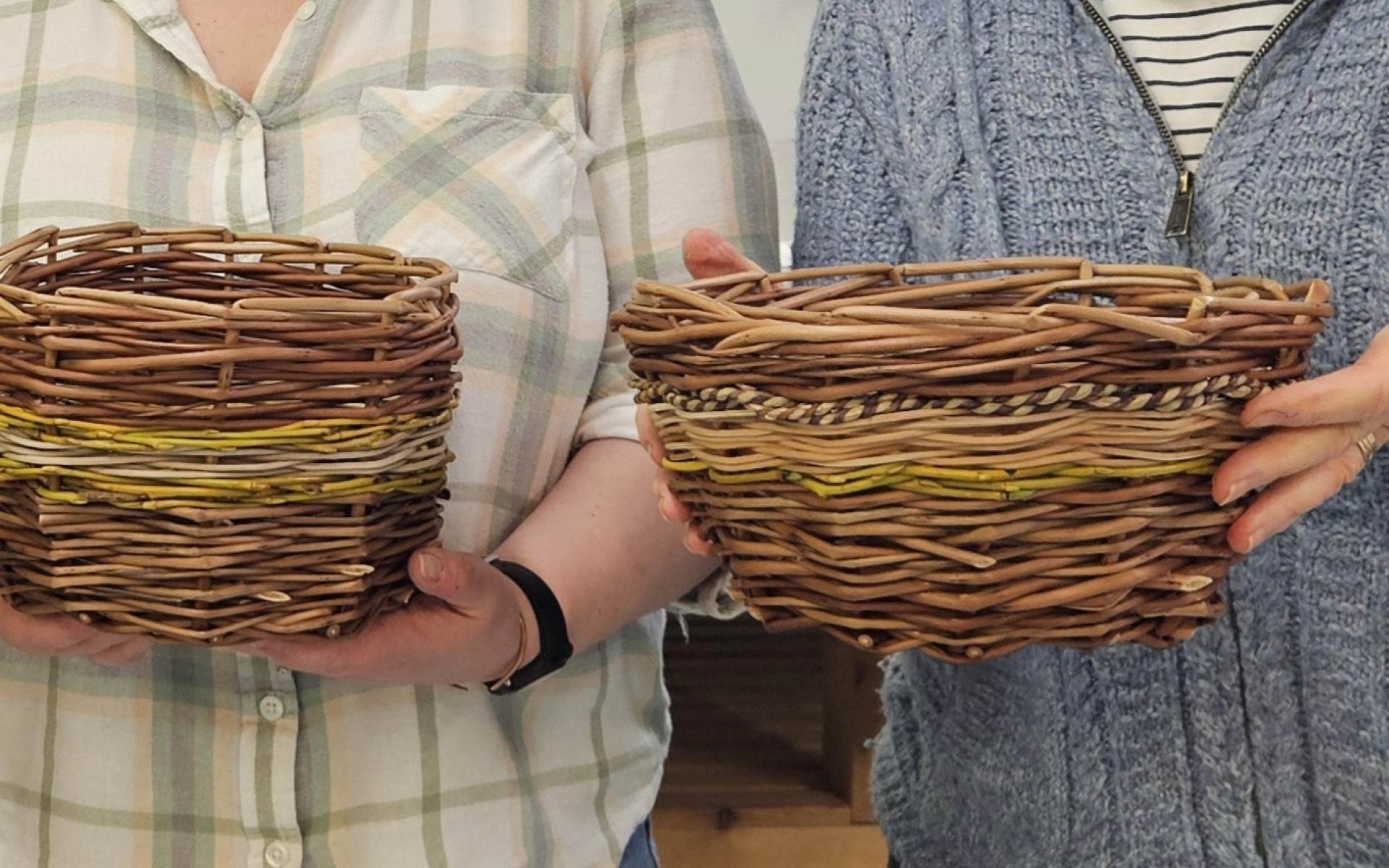 An image of two people holding their own woven wooden baskets in their hands.