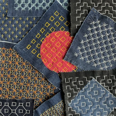 An image showing examples of square teal and dark green pieces of cloth, decorated with Sashiko Stitch pattern technique.